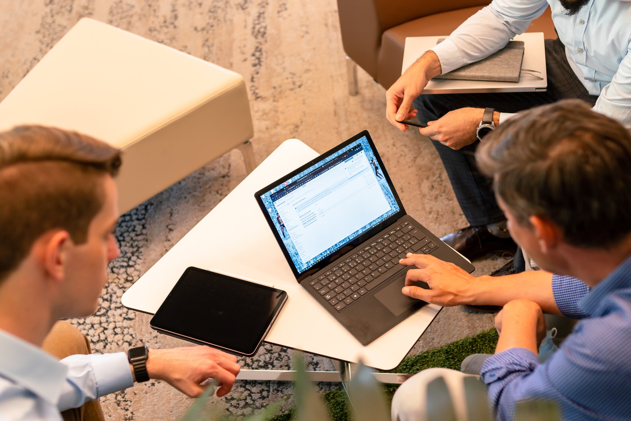 Menschen, die um einen Laptop und ein Tablet zusammenarbeiten