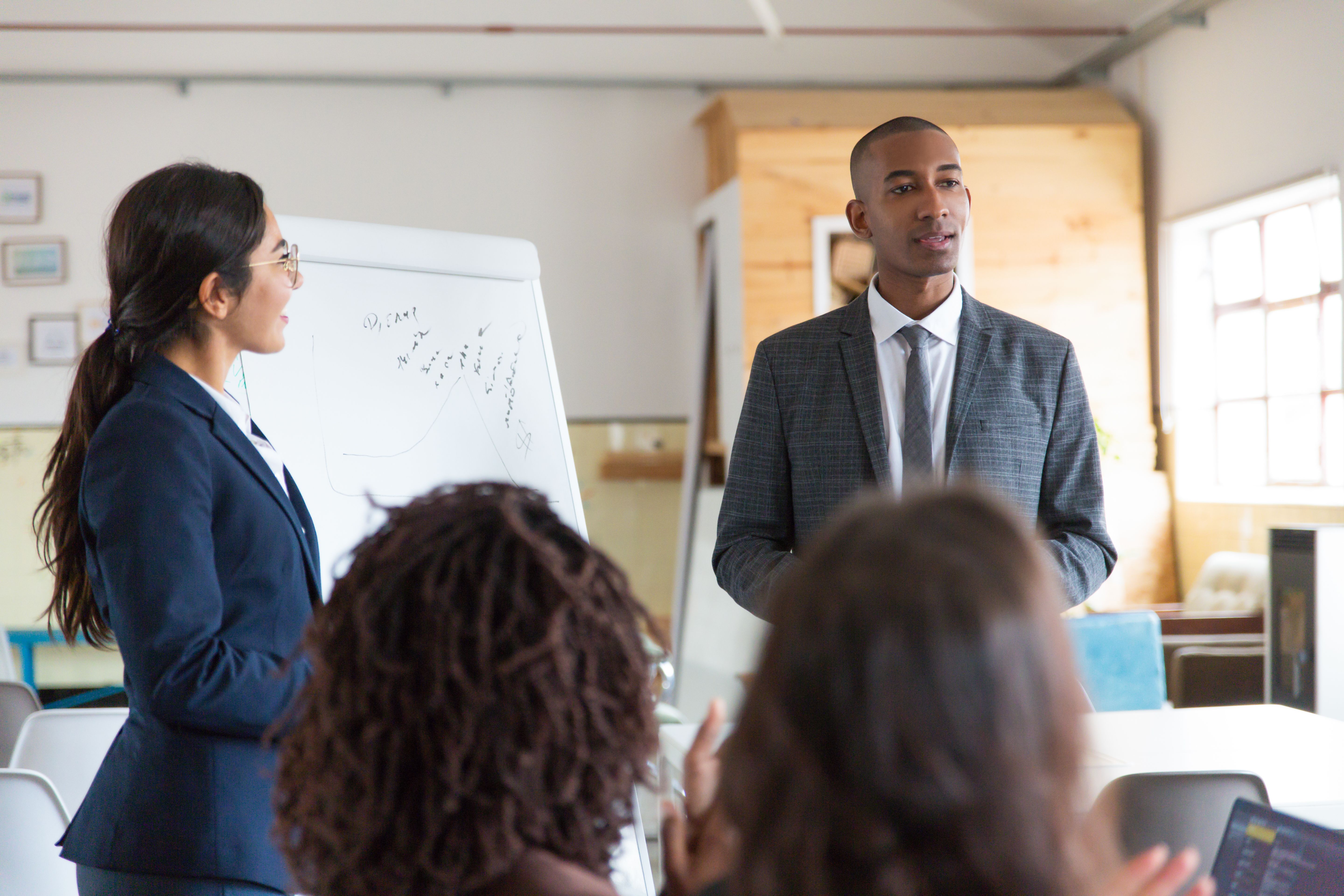 cheerful-young-speakers-standing-near-whiteboard.jpg