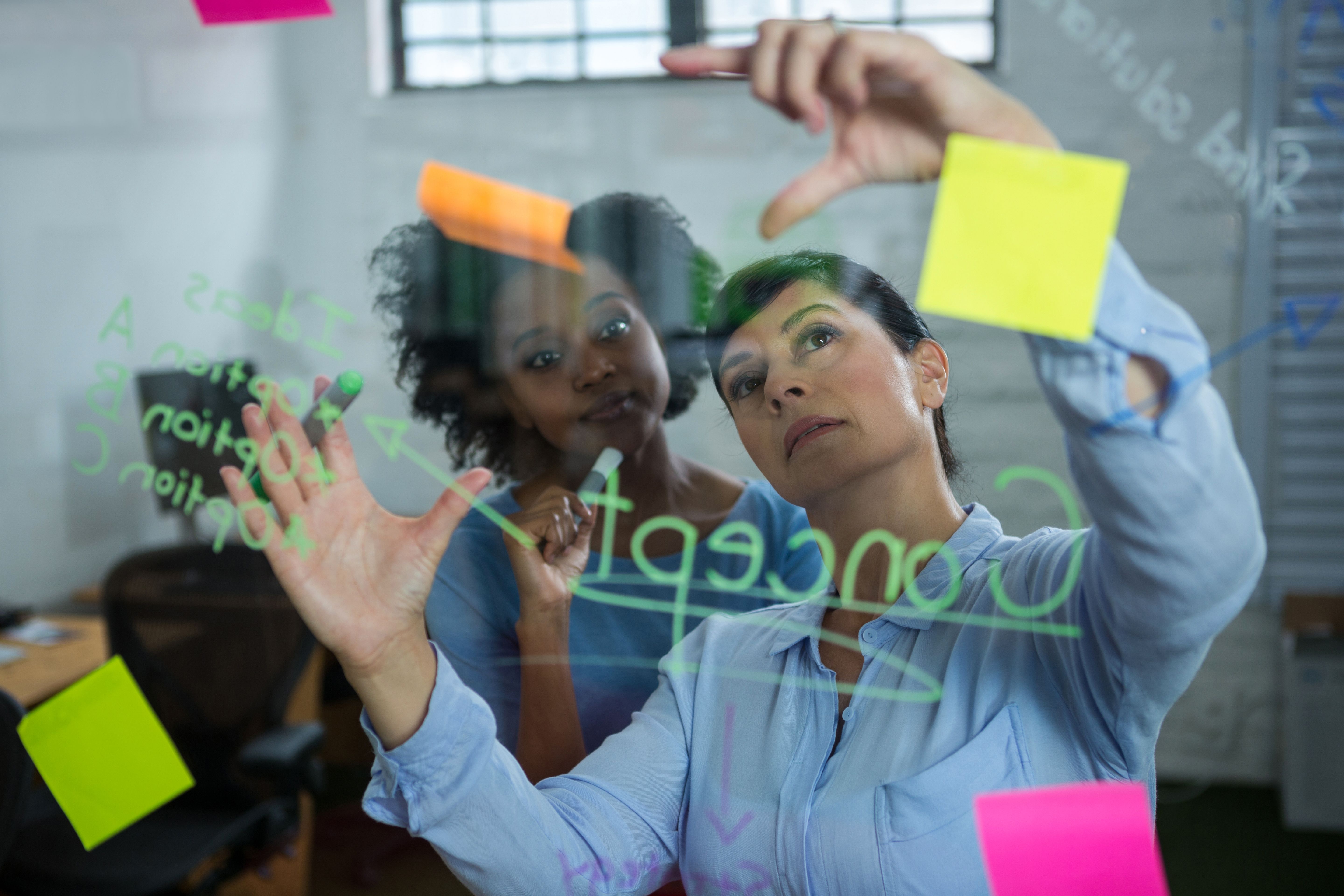 female-graphic-designer-pointing-sticky-notes-glass