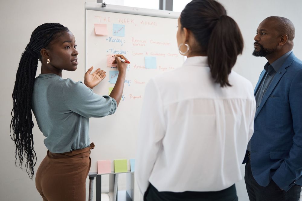 black-woman-business-schedule-whiteboard-writing-company-planning-with-sticky-notes-african-female-employee-startup-meeting-collaboration-staff-working-with-teamwork-conversation.jpg